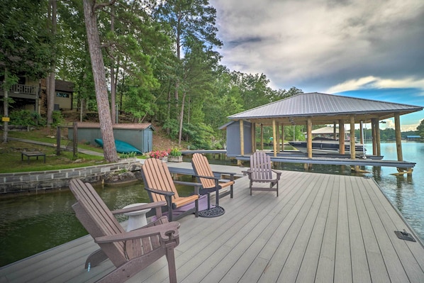Relax on the serene deck overlooking the lake, surrounded by mature trees and a tranquil atmosphere.