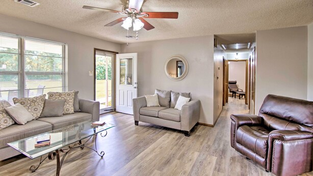 A spacious living room with a glass coffee table, a beige sofa, a brown leather armchair, and a ceiling fan. - Quiet Clayton Home w/ Mountain Views 4 Mi to Lake! (Clayton)