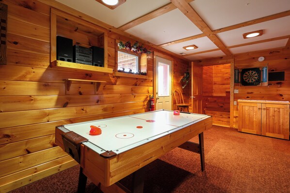 Un intérieur en bois avec une table de billard, un jeu de fléchettes et un petit coin bar.