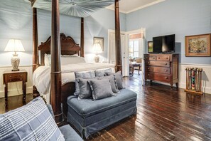 Ein Schlafzimmer mit einem Himmelbett, einer Bank, einem Schminktisch und einem Fernseher.