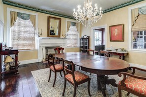 A formal dining room with a large wooden table, chairs, a chandelier, and a fireplace.