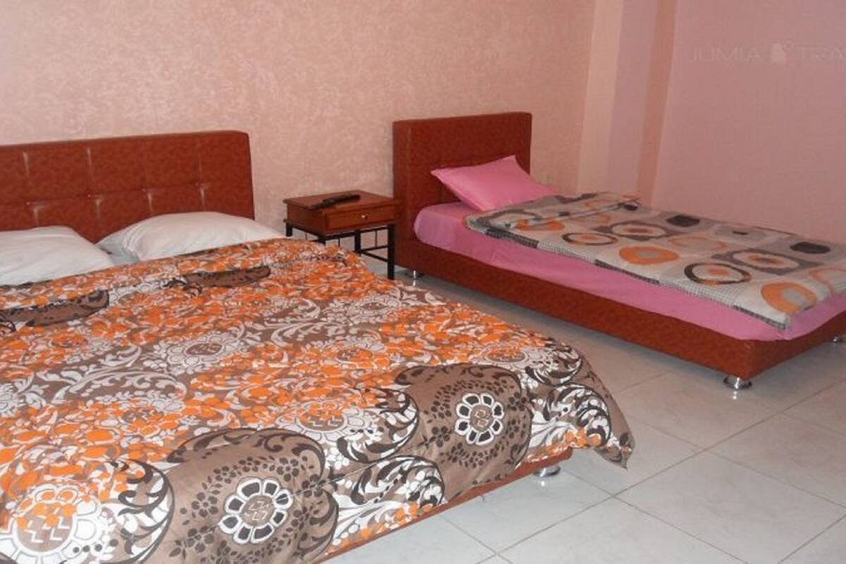 Een slaapkamer met twee bedden, waarvan één groter en één kleiner, beide met beddengoed met een patroon.