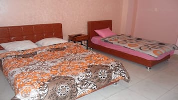 A bedroom with two beds, one larger and one smaller, both with patterned bedspreads.