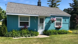 A single-story house with a gabled roof, a front porch, and a small front yard with a flower bed.