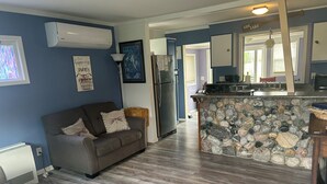 A modern kitchen with a stone island, a grey sofa, and a refrigerator.