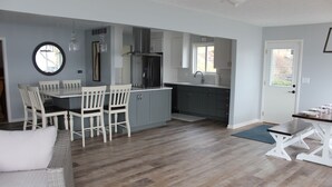 A modern kitchen with white cabinets, a dining area with white chairs, and a large window.