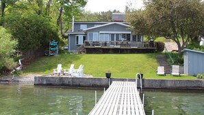 A dock leading to a house with a deck and outdoor seating.