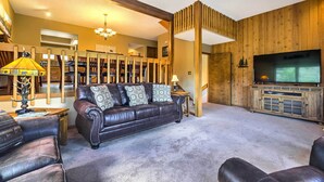 Un salon chaleureux avec un canapé en cuir, un téléviseur et un mur en bois.
