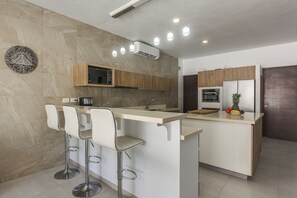 A modern kitchen with a central island, bar stools, a microwave, and a built-in oven. - 1 Mi to Beach: Luxe Playa Del Carmen Home w/ Pool (Playa Del Carmen)