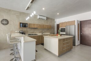Una cocina moderna con una isla central, electrodomésticos integrados y una zona de bar.