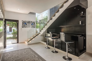 A modern interior with a staircase, a bar area, and a painting of a cat's eye. - 1 Mi to Beach: Luxe Playa Del Carmen Home w/ Pool (Playa Del Carmen)