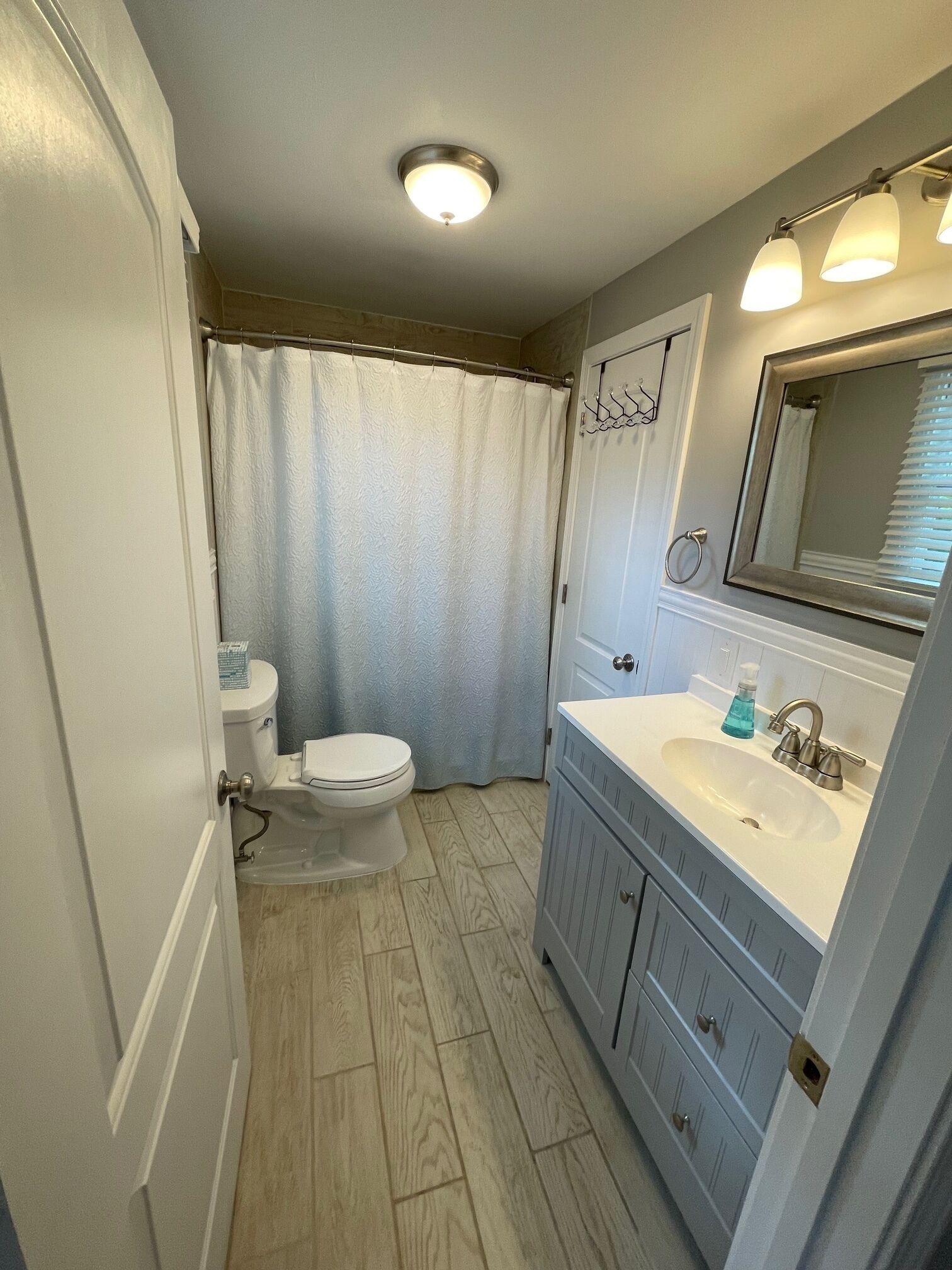A bathroom with a toilet, sink, and shower curtain.