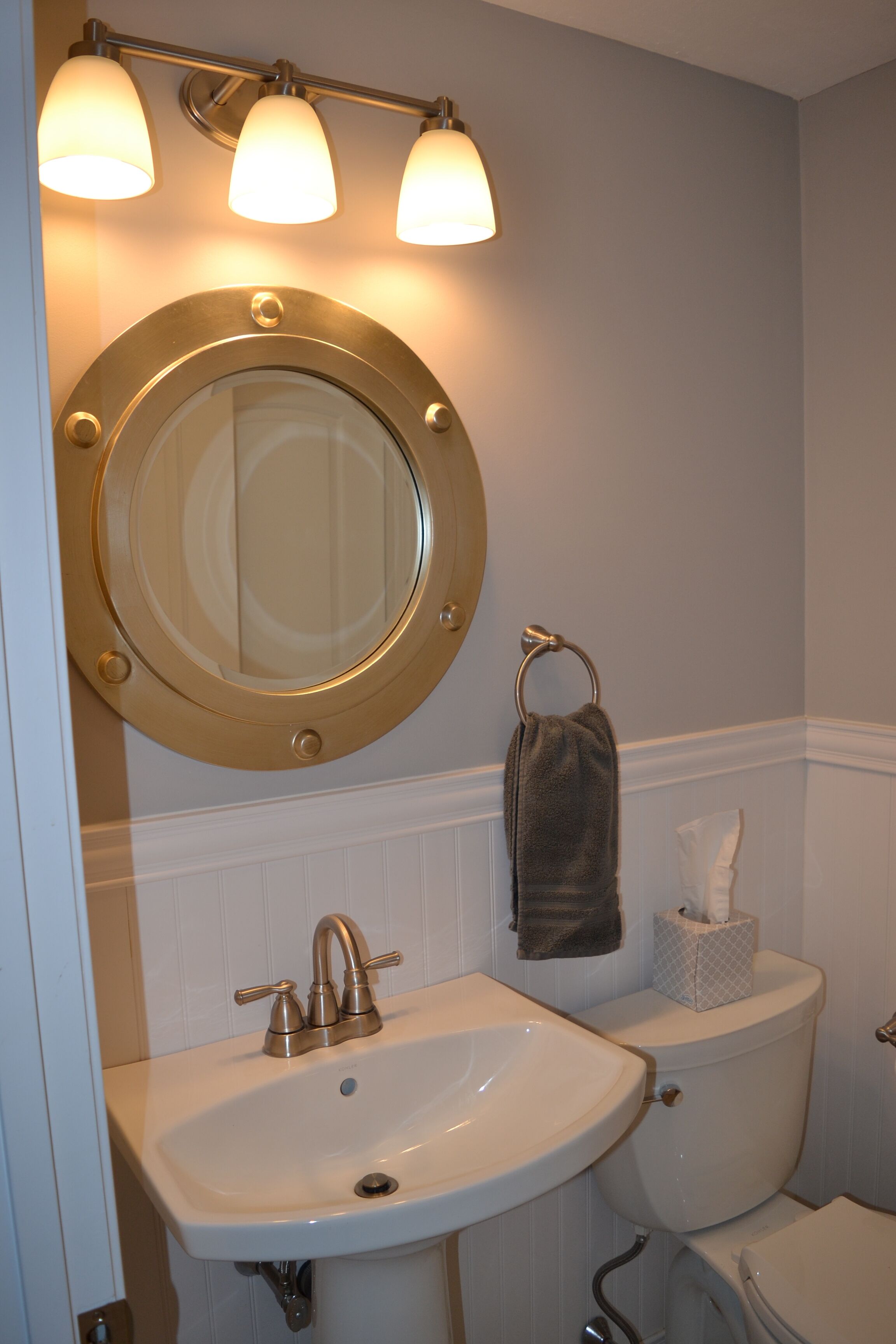 A bathroom with a round mirror, a sink, and a toilet.