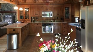 A spacious kitchen with wooden cabinets, stainless steel appliances, and a central island. - Beautiful, Peaceful Lakefront Home in woods. Canoe, Kayaks, ATV trail access. (Sangerville)