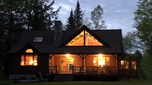 A lodge with a prominent front porch, large windows, and a stone chimney. - Beautiful, Peaceful Lakefront Home in woods. Canoe, Kayaks, ATV trail access. (Sangerville)