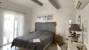 A bedroom with a bed, a desk, a chair, a lamp, and a picture on the wall.