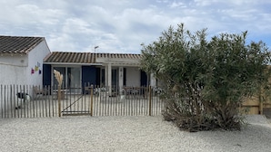 A rustic house with a tiled roof, a gravel driveway, and a wooden fence.