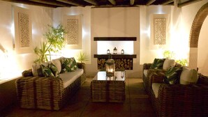 Un'accogliente area relax con mobili in vimini, un tavolino centrale con lanterne e pannelli decorativi a parete.