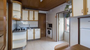 Una cocina compacta con armarios de madera, estufa, lavadora y refrigerador.