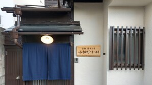 A traditional Japanese entrance with a sliding door, a signboard, and a small window with bars. - Komatsucho 11-41 (Kyoto)