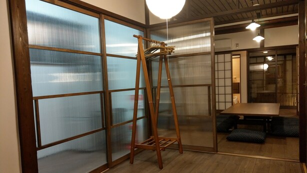 A room with sliding glass doors, a wooden ladder, a table with chairs, and a hanging light fixture. - Komatsucho 11-41 (Kyoto)