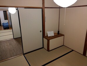 Una habitación japonesa tradicional con suelo de tatami, puerta corredera de shoji y una pequeña mesa de madera con un cartel.