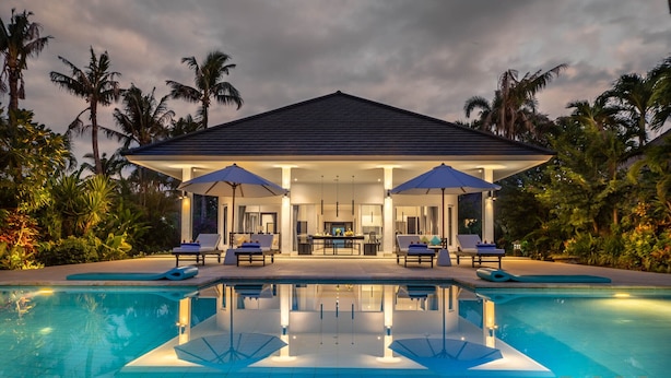 Un complexe hôtelier doté d’une piscine, de chaises longues, de parasols et d’un espace de restauration abrité.