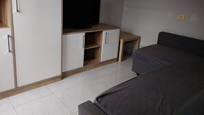 Een slaapkamer met een bed, een televisie op een houten dressoir en een kledingkast.