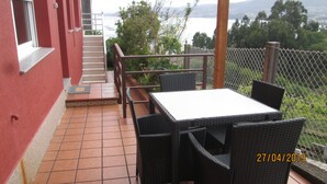 Een terras met een tafel en stoelen, een trap en uitzicht op een wateroppervlak.