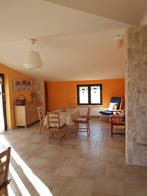 A dining area with a table and chairs, a stone wall, and a window with curtains.