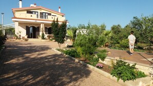 A two-story house with a tiled roof, a balcony, and a paved driveway.
