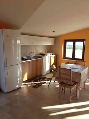 A kitchen with white cabinets, a refrigerator, a stove, and a dining table with chairs.