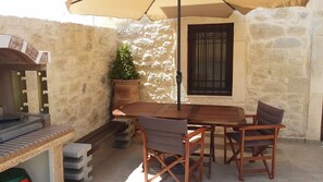 Relax outdoors with a meal at this patio area, featuring a table and chairs under a large umbrella.