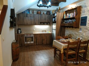 Enjoy a warm meal in this inviting kitchen with oven, coffee maker, and sink, complemented by a dining area with a wooden table and chairs.