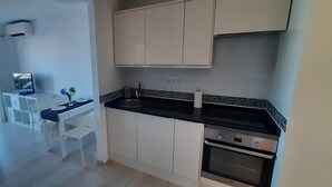 Une cuisine moderne avec des meubles blancs, un plan de travail noir et un four encastré.