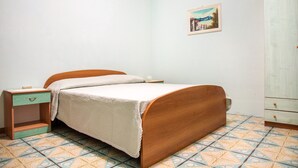Ein Schlafzimmer mit einem hölzernen Bett, einem Nachttisch, einer Kommode und einem gestreiften Boden.