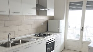 Eine moderne Küche mit weißen Schränken, einer Edelstahl-Spüle, einem Gasherd und einem eingebauten Backofen.