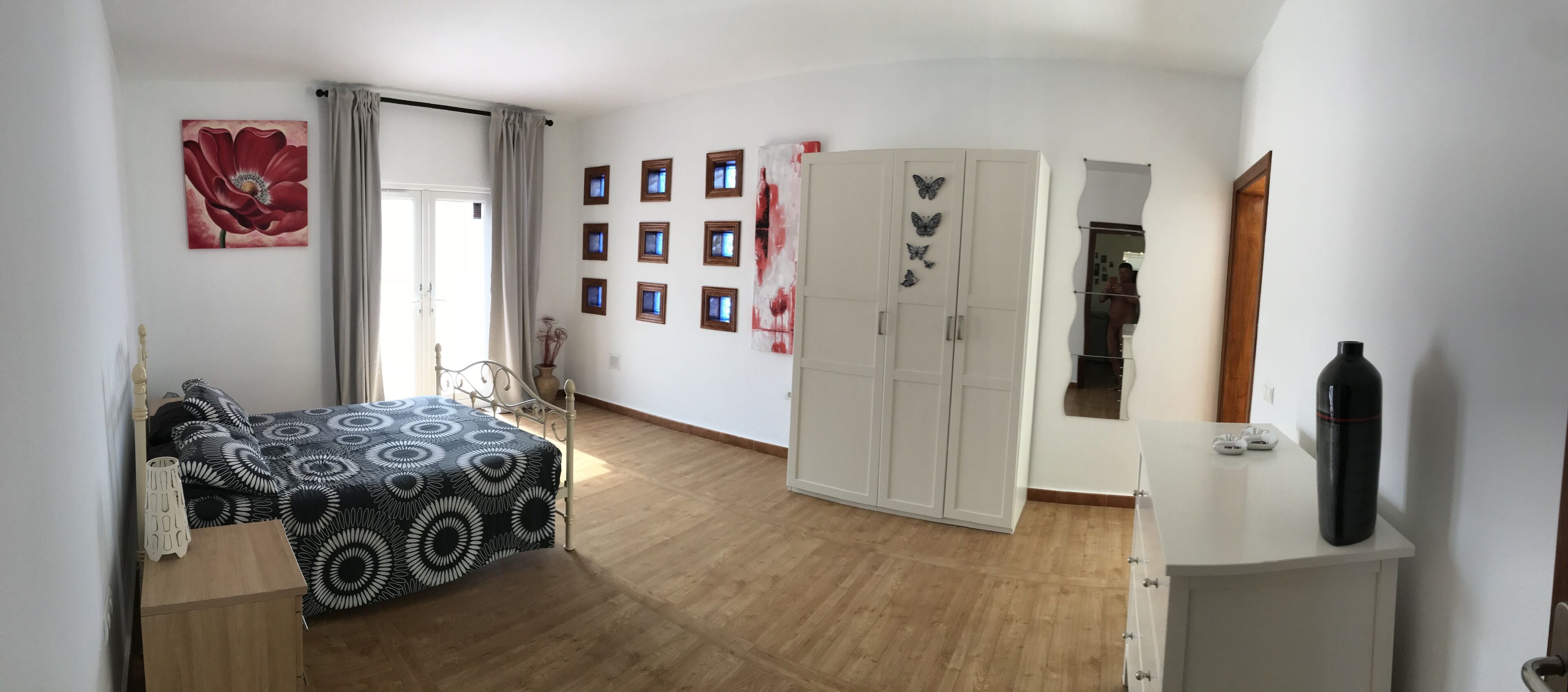 Una habitació amb llit, taula amb mantell estampat, armari i mirall.