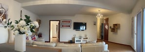 A modern living room with a sofa set, a flat-screen TV, and decorative items.