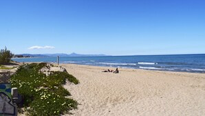 Una playa con arena, algunas personas y un cielo despejado.