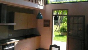 A kitchen with a stove, sink, and cabinets, a hanging light, and a view of greenery outside. - Typical regional house, fully and tastefully renovated with old bricks and beams, very sunny surrounded by old trees & vinyards, close to huge beaches & golf courses. (Messanges)