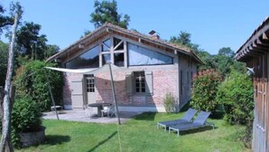 A two-story house with a brick exterior, a balcony, and a patio area with a table and chairs. - Typical regional house, fully and tastefully renovated with old bricks and beams, very sunny surrounded by old trees & vinyards, close to huge beaches & golf courses. (Messanges)