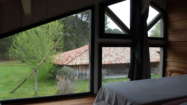 A bedroom with a large window, wooden floor, and a bed with a white bedspread. - Typical regional house, fully and tastefully renovated with old bricks and beams, very sunny surrounded by old trees & vinyards, close to huge beaches & golf courses. (Messanges)