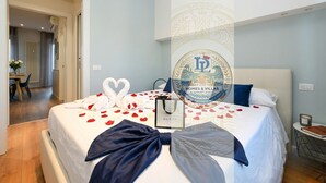 Habitación de hotel con cama, mesita de noche, una silla y vista a un pasillo.
