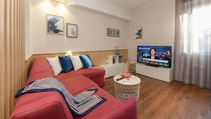 Una sala de estar moderna con un sofá rojo, un televisor de pantalla plana y una pequeña mesa redonda de centro.