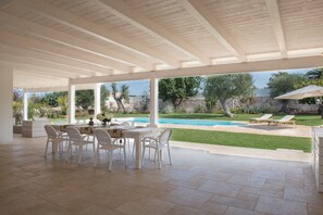 An open patio with a pool, white furniture, and a view of the garden. - Villa Greta in Polignano a Mare, maximum relaxation in nature between sea and countryside (Polignano a Mare)