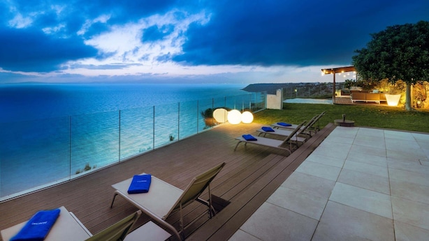 Una terraza con sillones de descanso, una mesa y vistas al mar.
