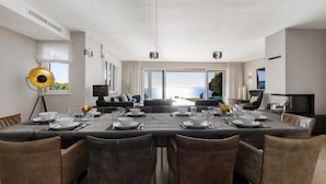 Un comedor moderno con una mesa larga, varias sillas y vista al mar.