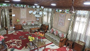 A cozy living room with a patterned sofa, a wooden coffee table, and a chandelier. - Appollo eleven group of houseboats (Srinagar)
