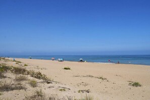 Une plage avec un ciel dégagé, un rivage sablonneux et quelques parasols.